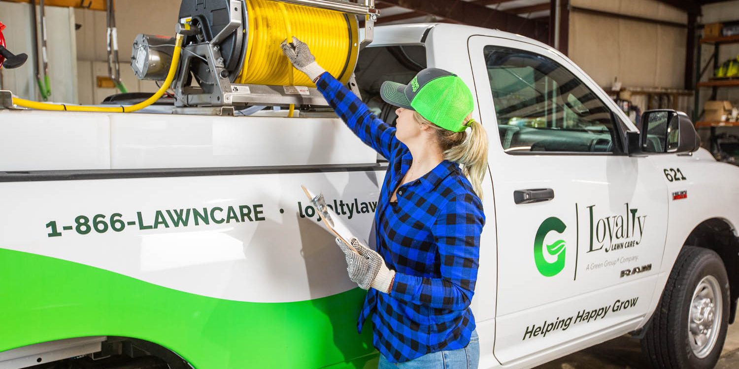 jwinkphoto-9501 A woman checking a hose on the back of a lawncare truck